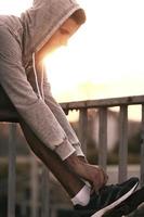 Preparing to run. Close-up of man tying shoelaces on sports shoe while standing outdoors photo