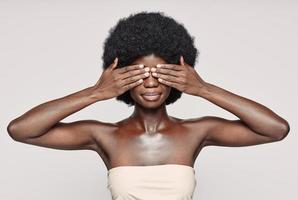 Portrait of beautiful young African woman covering eyes with hands photo