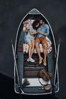 Loving couple. Top view of beautiful young couple embracing and smiling while lying in the boat photo