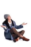 What a surprise Beautiful young cheerful woman in beany keeping arms outstretched and looking up with smile while sitting against white background photo