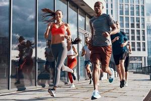toda la longitud de la gente con ropa deportiva trotando mientras hace ejercicio en la acera al aire libre foto