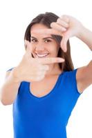 Focusing at you. Beautiful young smiling woman looking at camera and pointing you while standing isolated on white photo