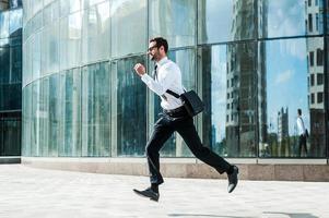 Hurrying to work. Full length of young businessman looking forward while running along the street photo