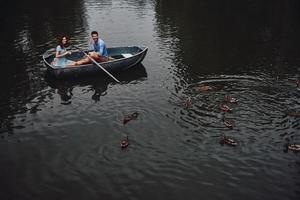 tan feliz vista superior de una hermosa pareja joven alimentando patos mientras disfruta de una cita romántica en el lago foto