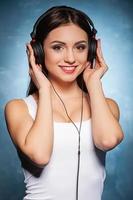 Music is my life. Beautiful young woman holding headphones and smiling photo