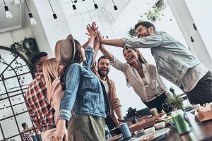 Real friends. Group of young people giving each other high-five in a symbol of unity and smiling while having a dinner party photo