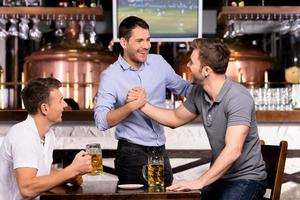 Old friends meeting. Three cheerful friends meet each other in beer pub photo