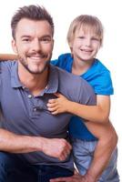 Cheerful father and son. Happy little boy embracing his father and smiling while both standing isolated on white photo