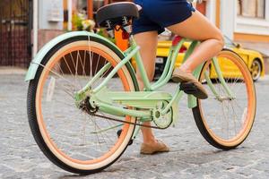 Ready to ride. Close-up of young woman riding bicycle along the street photo