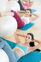 preparando cuerpos para la temporada de verano. vista superior de tres hermosas mujeres jóvenes en ropa deportiva haciendo ejercicio con pelota de fitness mientras se acuesta en colchonetas de ejercicio y mira la cámara foto