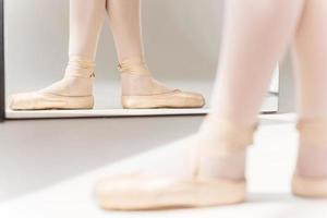 Perfect position. Close-up of ballerina legs in slippers standing against mirror photo