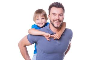 feliz padre e hijo. feliz padre cargando a su hijo en la espalda y sonriendo mientras ambos están aislados en blanco foto