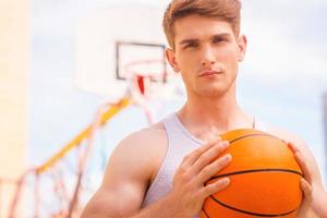 concentrarse antes del juego. guapo joven jugador de baloncesto masculino listo para el tiro foto