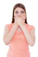 Shocked and frustrated. Shocked young woman covering mouth with hands while standing isolated on white photo
