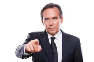 Businessman choosing you. Portrait of confident mature man in formalwear looking at camera and pointing you while standing against white background photo