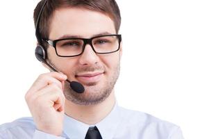 representante de servicio al cliente confiado. Apuesto joven en auriculares mirando a la cámara mientras está de pie aislado en blanco foto