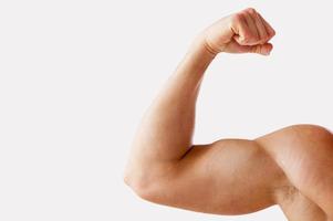 Perfect bicep. Close-up of muscular man showing his perfect bicep while standing against grey background photo