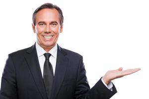 Businessman holding copy space. Happy mature man in shirt and tie holding copy space on his hand and smiling while standing isolated on white background photo