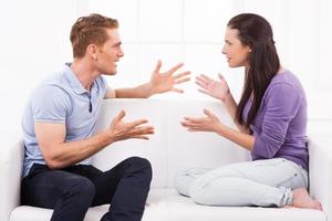 Confrontational couple. Furious young man and woman shouting at each other and gesturing while sitting on the couch photo