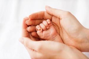 pequeña mano pequeña. primer plano de padre sosteniendo una pequeña mano de su pequeño bebé foto