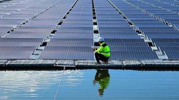 mannetje elektricien in wit veiligheid helm staand Aan ladder en montage fotovoltaïsche zonne- paneel onder mooi blauw lucht. concept van alternatief bronnen van energie. video