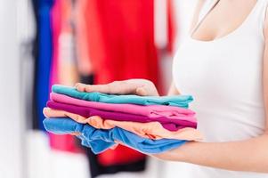 pila de ropa colorida. imagen recortada de una mujer sosteniendo una pila de ropa multicolor foto