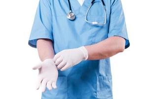 Preparing to surgery. Close-up of surgeon wearing surgical gloves while standing isolated on white photo