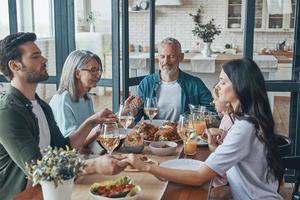 Happy multi-generation family holding hands and praying before having dinner together photo