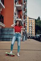 Getting ready to roll. Full length of attractive young woman smiling and looking at camera while standing outdoors photo