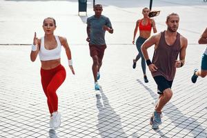vista superior de personas con ropa deportiva trotando mientras hacen ejercicio en la acera al aire libre foto
