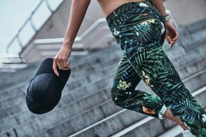 In style. Close-up of young woman carrying a cap while going up the stairs outdoors photo