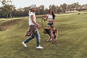 Happy to be together. Full length of beautiful young couple playing with their dog while spending time outdoors photo