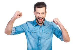 Happy winner. Happy young handsome man gesturing and keeping mouth open while standing against white background photo