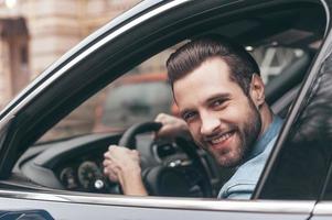 buen viaje. joven seguro de sí mismo sonriendo y mirando a la cámara mientras conduce un camión foto