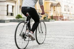 el transporte urbano perfecto. primer plano, de, joven, sentado, en, el suyo, bicicleta, mientras, equitación, por, el, calle foto