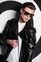 Cool and trendy. Handsome male model in leather jacket posing against target background photo