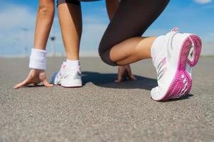 preparándose para correr. imagen de primer plano de una mujer con zapatos deportivos parada en la línea de salida foto