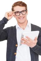 Confident in his gadget. Handsome young man holding digital tablet and smiling while standing isolated on white photo