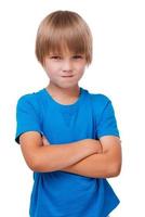 Naughty little boy. Sad little boy keeping arms crossed while standing isolated on white photo