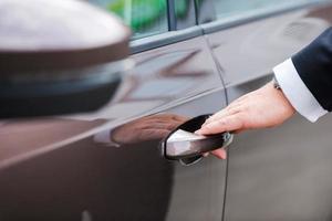 Hand on handle. Close-up of man in formalwear opening vehicle door photo