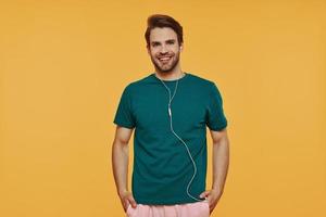 Handsome young man in headphones looking at camera and smiling photo