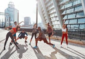 Full length of people in sports clothing warming up and stretching while exercising outdoors photo