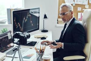 Senior man in elegant business suit using modern technologies while making social media video photo