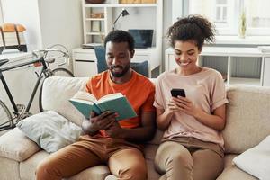 hermosa joven pareja africana disfrutando de sus pasatiempos mientras pasa tiempo en casa foto