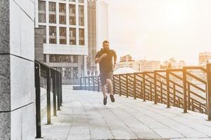 Out for a run. Full length of young man in sport clothing jogging while exercising outside photo