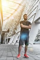 Music opens up a mind. Full length of handsome young man in sport clothing keeping arms crossed and looking away while standing outside photo