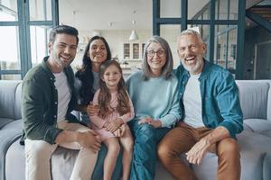 familia feliz pasando tiempo juntos y sonriendo mientras se sienta en el sofá en casa foto