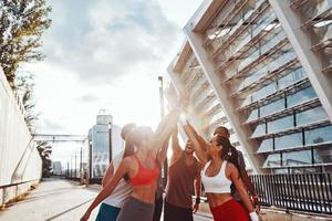 grupo de jóvenes en ropa deportiva tomados de la mano mientras están de pie al aire libre foto