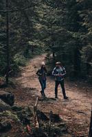 pareja aventurera. toda la longitud de una hermosa pareja joven caminando juntos en el bosque mientras disfrutan de su viaje foto