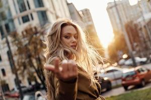 Irresistible girl. Attractive young smiling woman looking at camera and gesturing while standing outdoors photo